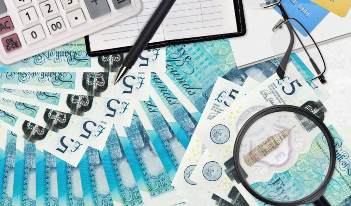 5 British pounds bills and calculator with glasses and pen. Tax payment season concept or investment solutions. Searching a job with high salary